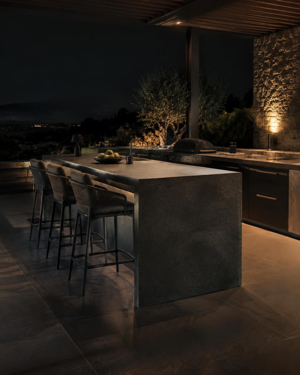 Concept freestanding outdoor kitchen island with bar seating at night